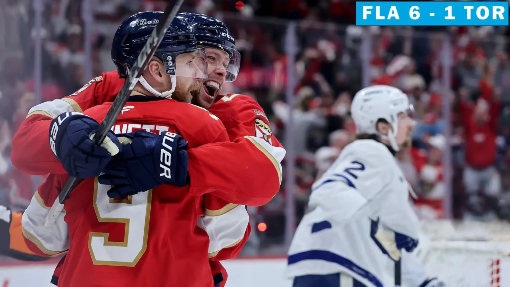 Two Florida Panthers players in red jerseys embrace and cheer on the ice, celebrating a goal. In the background, a dejected Toronto Maple Leafs player in a white jersey skates away from the net. The scoreboard in the top right corner shows "FLA 6 - 1 TOR."
