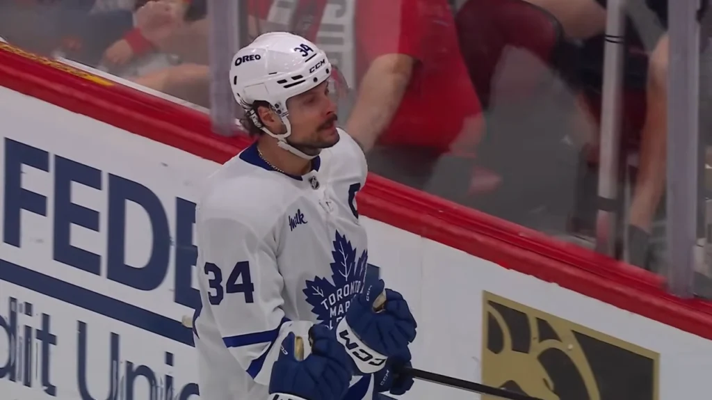A close-up of a hockey player Max Pacioretty in a white Toronto Maple Leafs jersey with the number 34, celebrating goal.