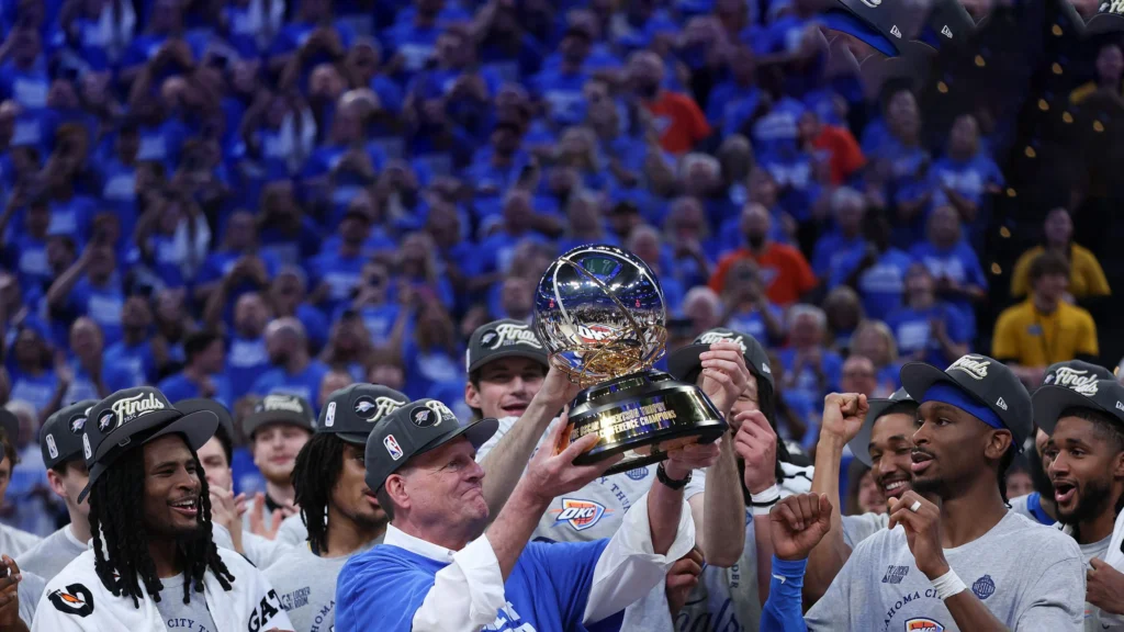 Owner Clay Bennett of the Oklahoma City Thunder raises the Oscar Robertson Trophy with the team after defeating the Minnesota Timberwolves 124-94 in Game Five of the Western Conference Finals.