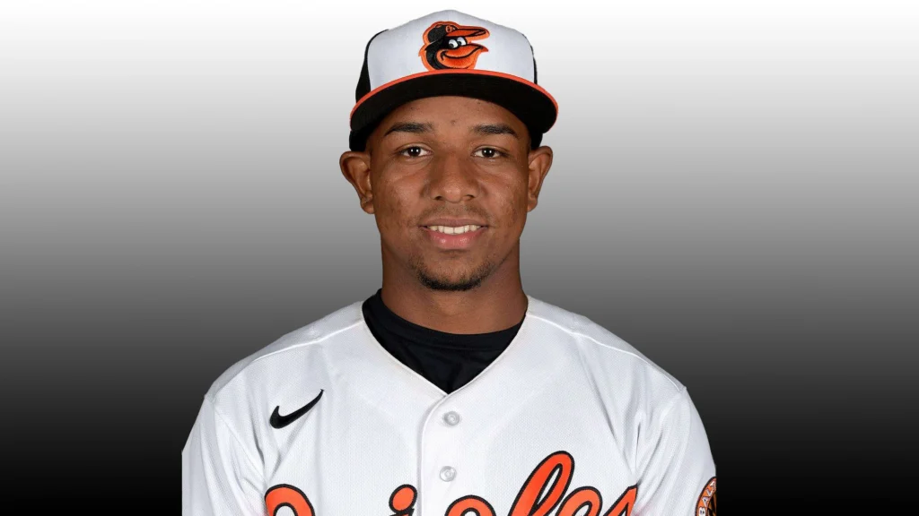 A young male baseball player, Luis Guevara, wearing a white Baltimore Orioles jersey and cap, smiling slightly for a headshot against a gray background.