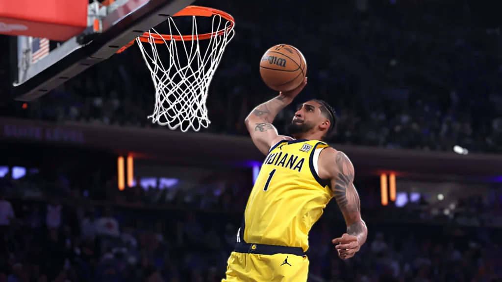 Indiana Pacers player Obi Toppin, wearing a yellow jersey with number 1, is in mid-air about to dunk a basketball into the hoop. He is looking focused with his arm extended over his head, holding the ball. The basketball court and crowd are blurred in the background.