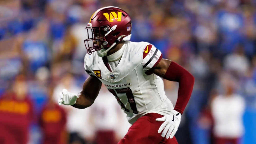 Terry McLaurin, wearing a white Washington Commanders jersey with burgundy accents and a matching helmet with the W logo, in a dynamic pose during a game.